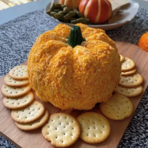 Pumpkin cheese ball appetizer, coated in pecans, served with crackers.