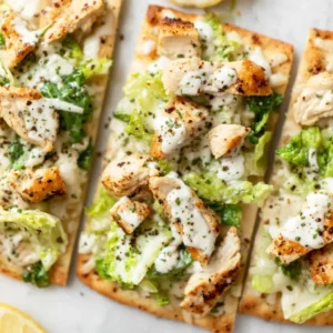 A delicious Chicken Caesar Flatbread features creamy Caesar dressing, grilled chicken, and fresh romaine lettuce.