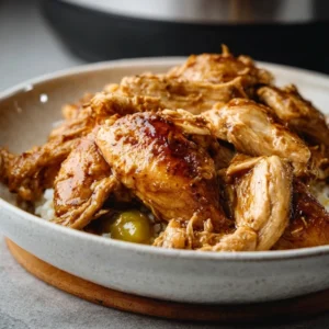 GAME CHANGING INSTANT POT MISSISSIPPI CHICKEN 5 Shredded Instant Pot Mississippi Chicken in a white bowl, garnished with pepperoncini peppers.