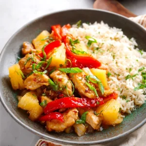 A delicious bowl of Ginger Soy Pineapple Chicken Stir-Fry with fresh pineapple, bell peppers, and sesame seeds.